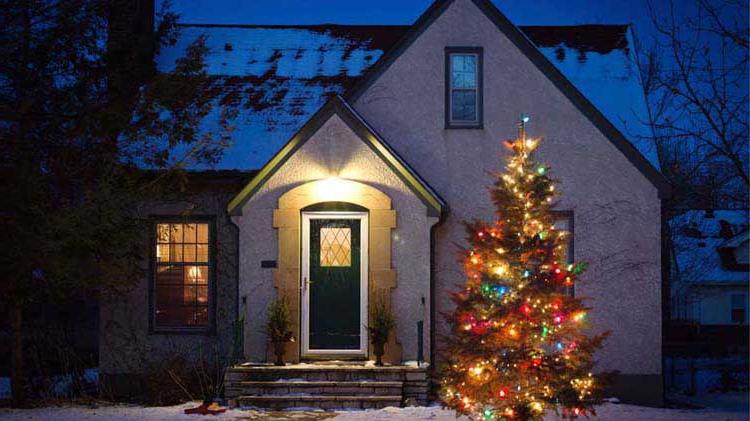 晚上舒适的房子，外面有一棵点亮的圣诞树.