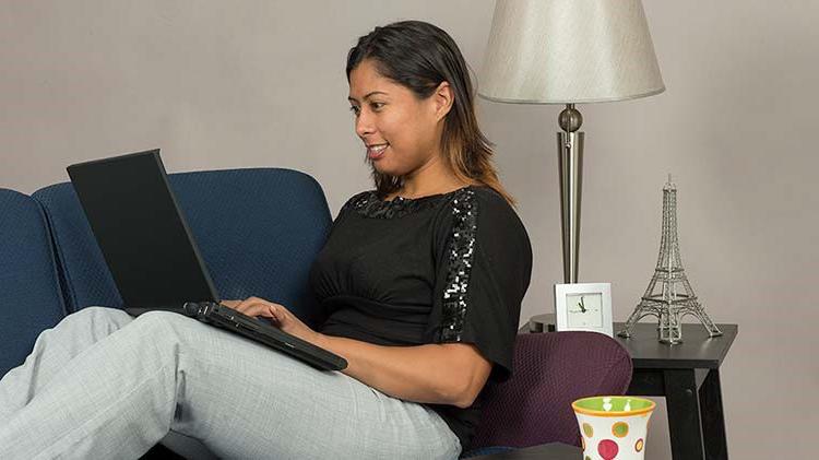 一个女人斜倚在沙发上，用笔记本电脑完成屏幕截图.